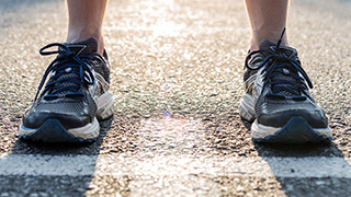 Ett par ben och fötter iklädda gympaskor står på en startlinje.